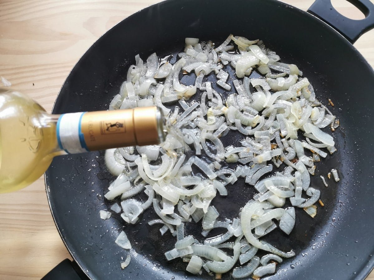 White onions fried in a deep frying pan.