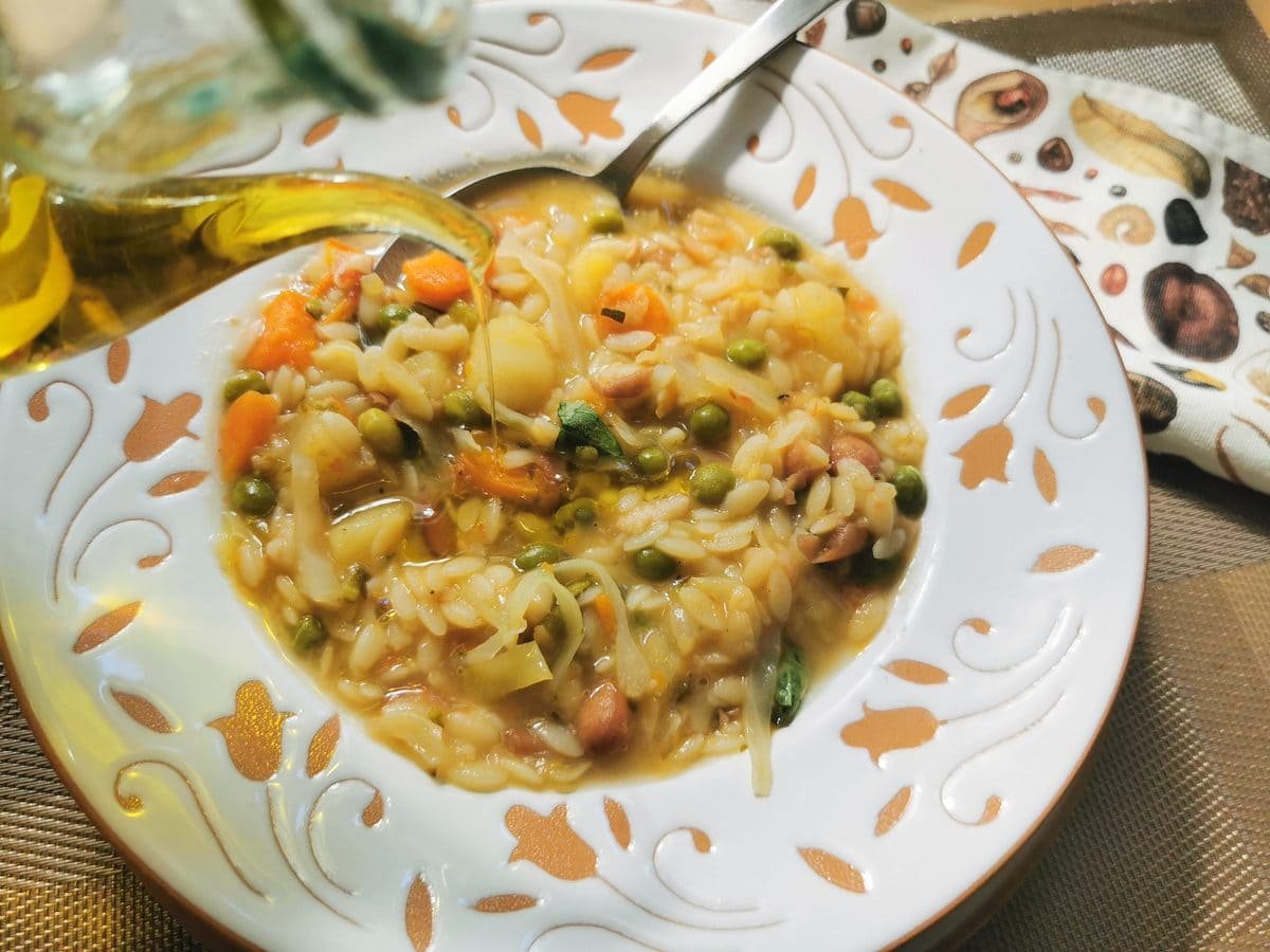 Minestrone Milanese in white and orange bowl.