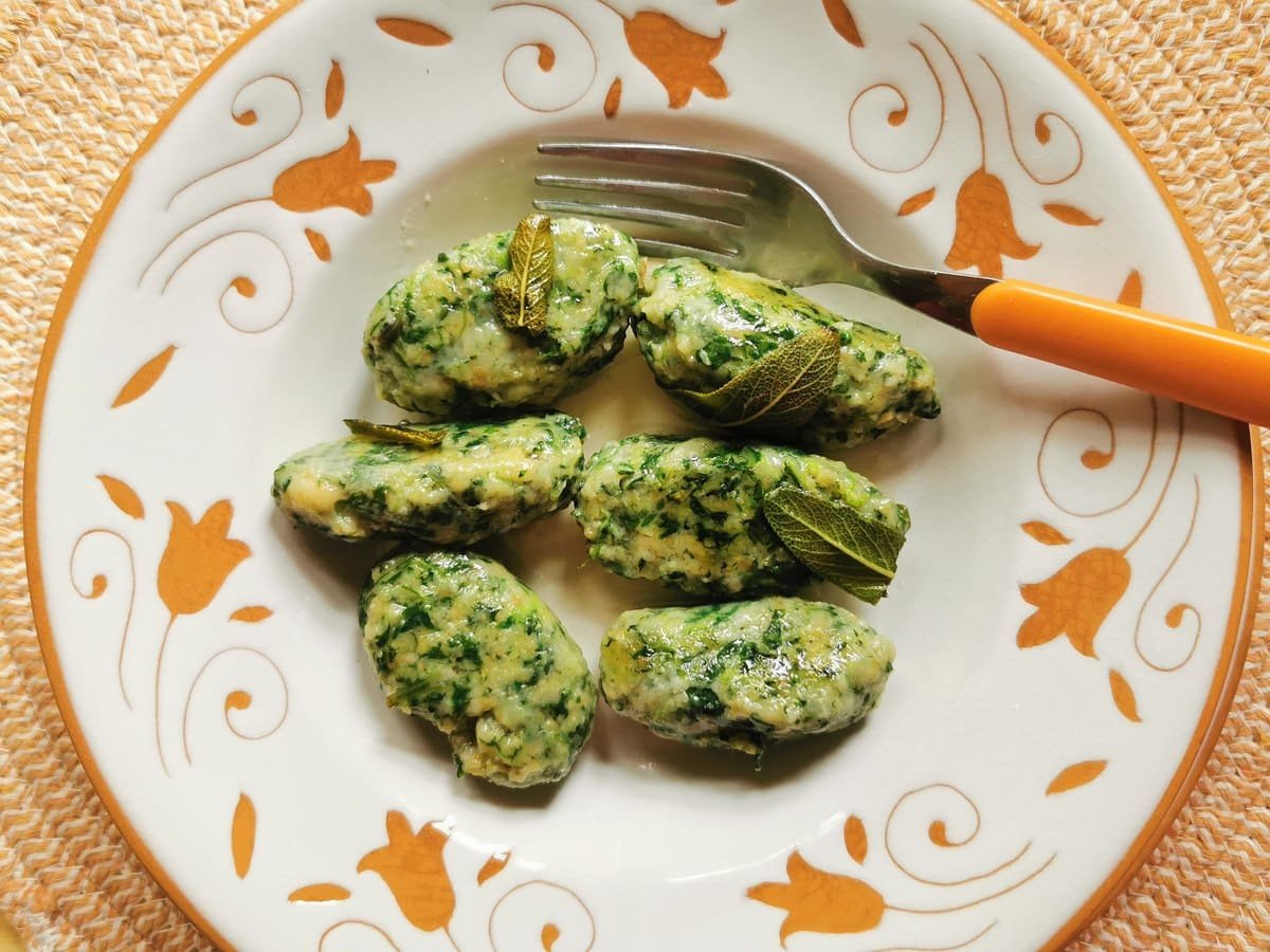 Strangolapreti gnocchi from Lombardy in a white and orange bowl.