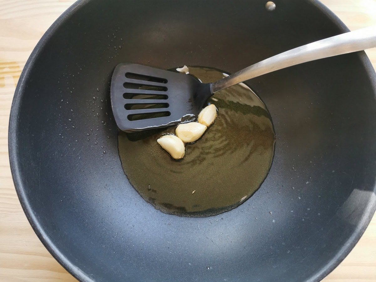 Peeled garlic cloves that cook in deep frying pan with olive oil.