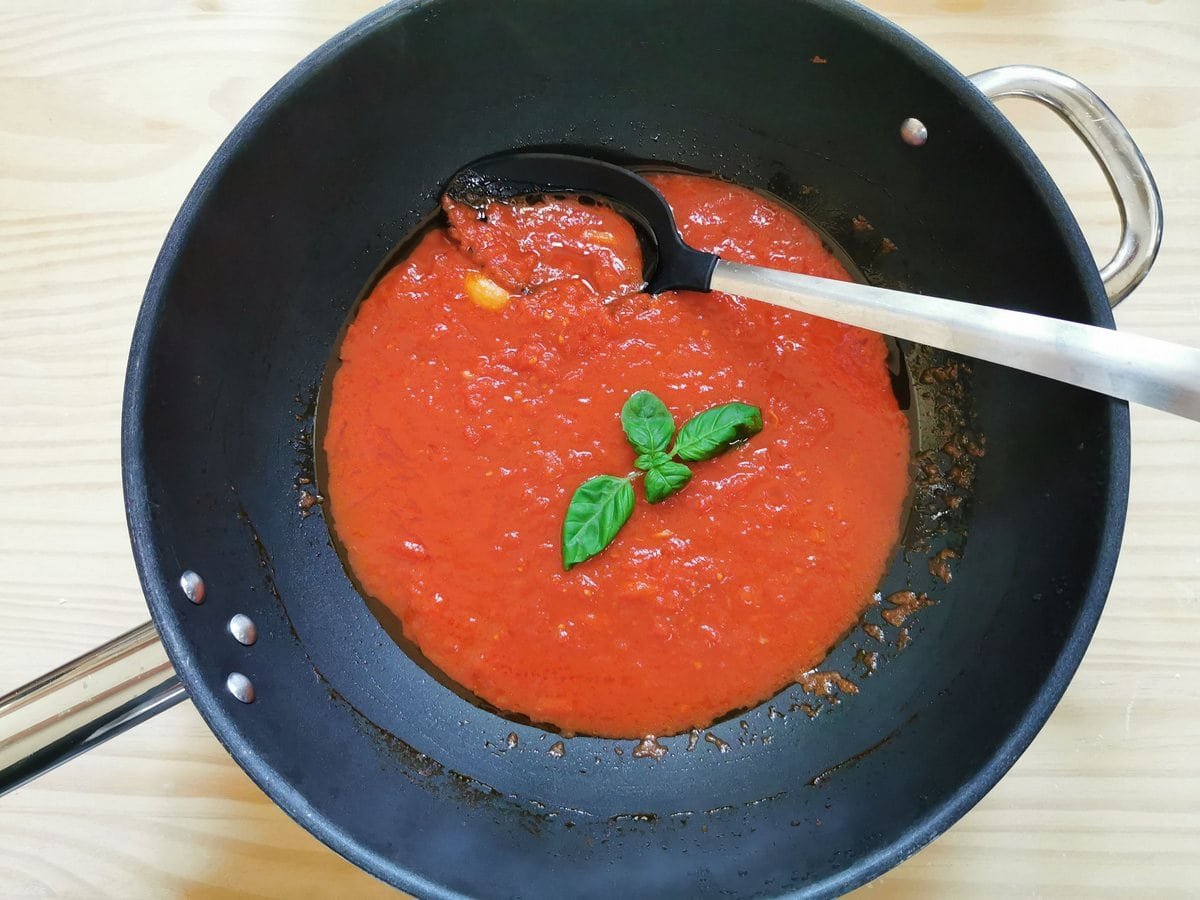 Clear Pomodoro sauce in frying pan with added fresh basil leaves.